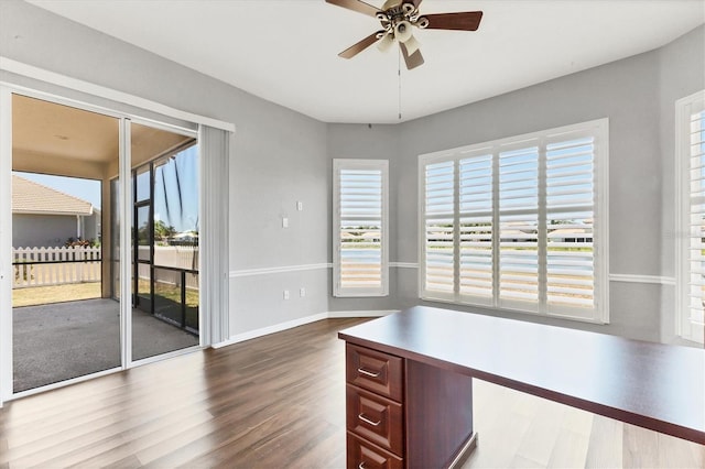 unfurnished office featuring baseboards, dark wood-style flooring, and a ceiling fan