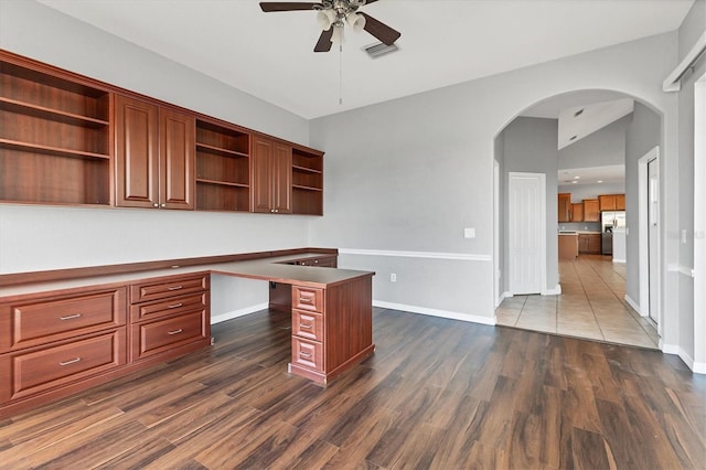 unfurnished office with visible vents, dark wood-style flooring, arched walkways, a ceiling fan, and baseboards