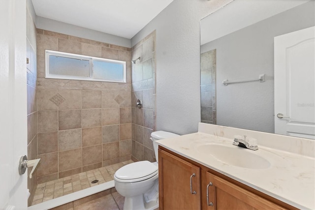 full bath featuring toilet, tiled shower, and vanity