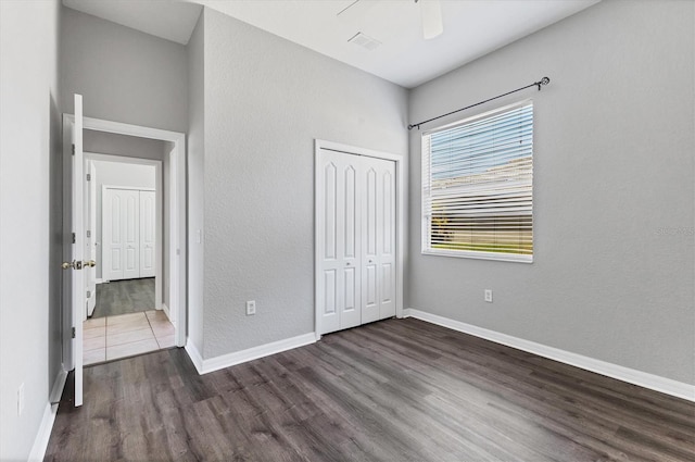 unfurnished bedroom with ceiling fan, a closet, baseboards, and wood finished floors