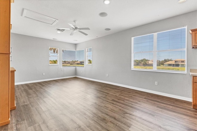 empty room featuring attic access, baseboards, and wood finished floors