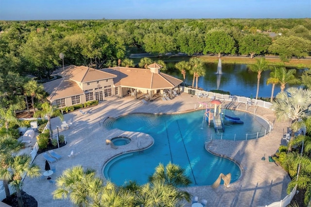 community pool featuring a water view, a forest view, and a hot tub