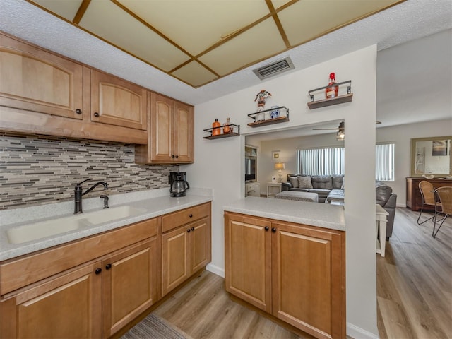 340 Base Ave E Unit 314, Venice, FL 34285 - kitchen featuring a sink, light wood-style flooring, open floor plan, decorative backsplash, and visible vents