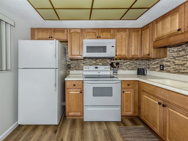 340 Base Ave E Unit 314, Venice, FL 34285 - kitchen with dark wood-style flooring, white appliances, light countertops, brown cabinetry, and tasteful backsplash
