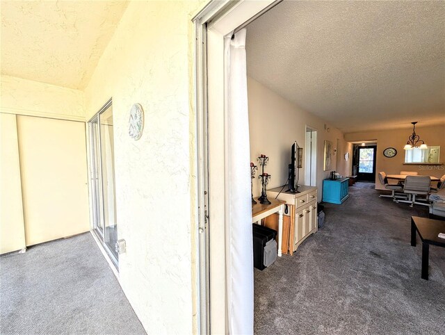 3559 Lake Bayshore Dr Unit J-204, Bradenton, FL 34205 - hallway featuring a textured wall, dark colored carpet, a textured ceiling, and a notable chandelier