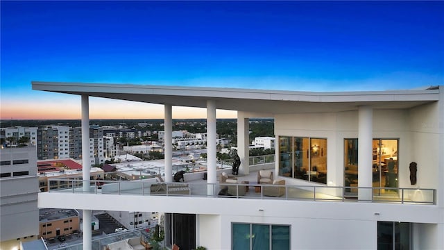 back of house with a balcony, a city view, and stucco siding