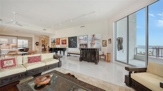 tiled living room featuring rail lighting, healthy amount of natural light, a ceiling fan, and a water view