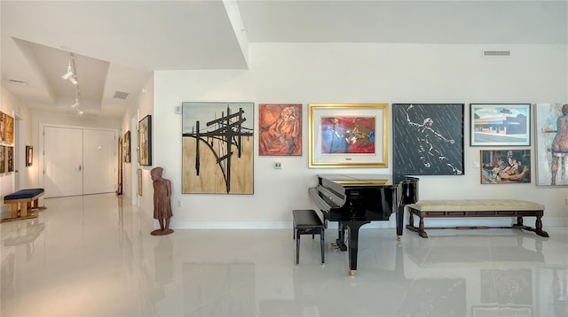 living area with rail lighting, tile patterned flooring, and baseboards