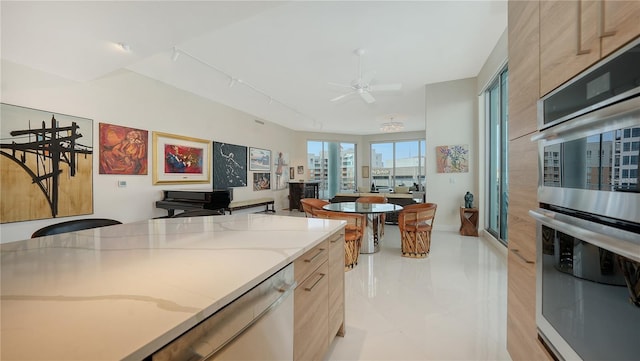 kitchen featuring double oven, ceiling fan, light stone counters, dishwashing machine, and light tile patterned flooring