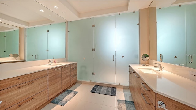 full bath featuring a tray ceiling, two vanities, and tile patterned floors