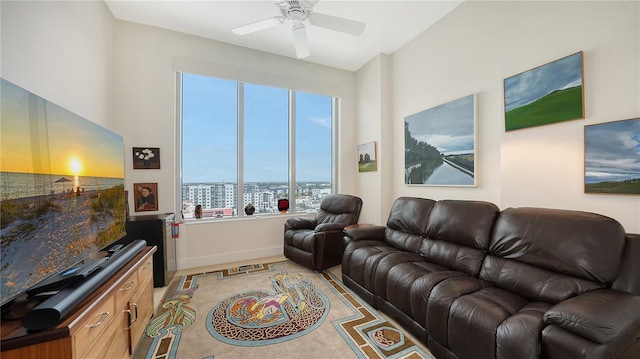 living area featuring a ceiling fan, baseboards, light colored carpet, and a city view