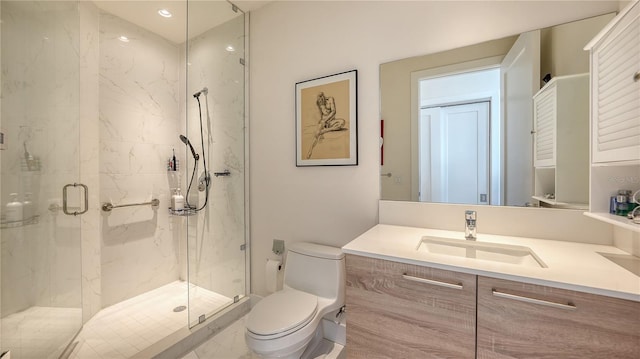 bathroom featuring toilet, a marble finish shower, and vanity