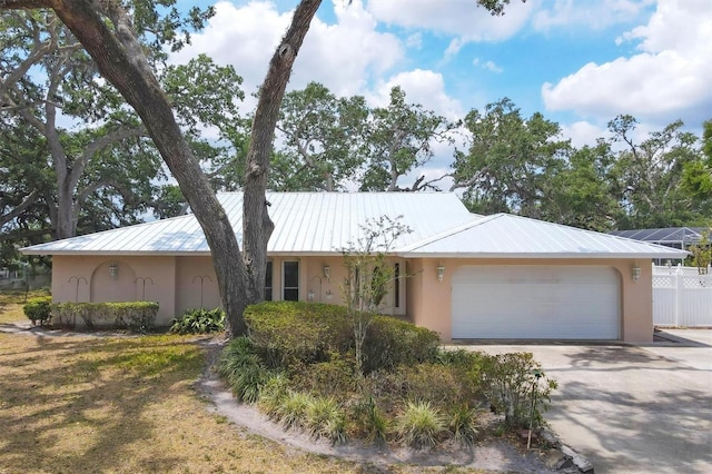 ranch-style home featuring stucco siding, a garage, and metal roof