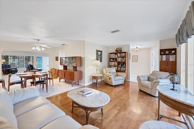 living area featuring a ceiling fan, light wood-type flooring, and baseboards