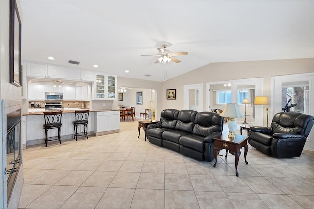 living area with a ceiling fan, light tile patterned floors, lofted ceiling, recessed lighting, and a fireplace