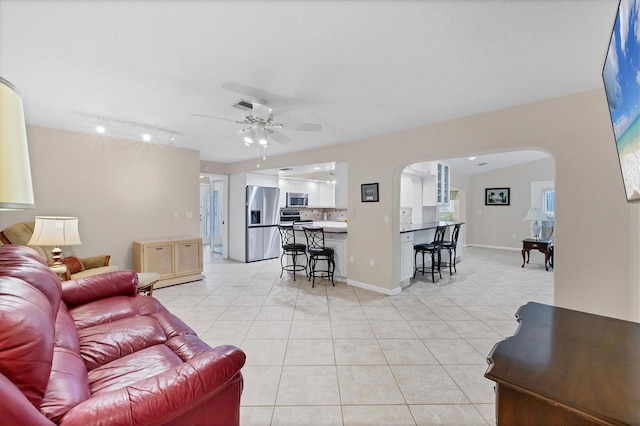 living area featuring arched walkways, track lighting, light tile patterned flooring, and ceiling fan