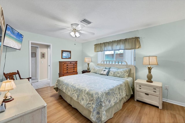 bedroom featuring light wood-style flooring, baseboards, a ceiling fan, and a textured ceiling