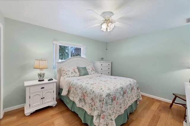 bedroom featuring baseboards, light wood-style floors, and a ceiling fan