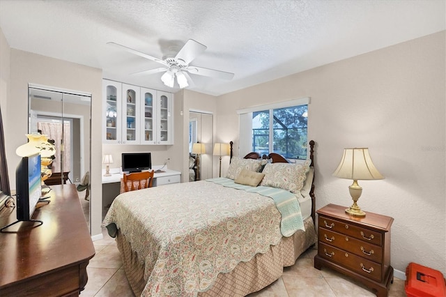 bedroom with light tile patterned floors, a desk, ceiling fan, and a textured ceiling