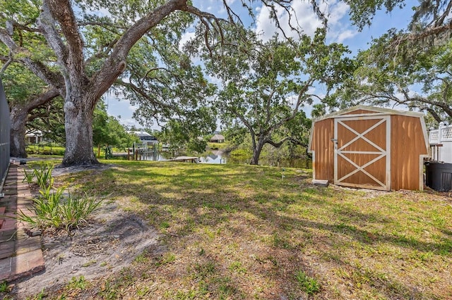 view of grassy yard featuring a water view, a storage shed, and an outdoor structure
