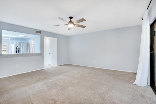 spare room featuring a ceiling fan, light colored carpet, visible vents, and baseboards