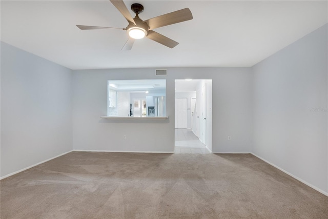 carpeted empty room with baseboards, a ceiling fan, and visible vents