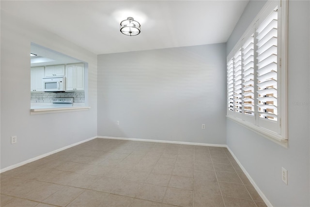 unfurnished dining area featuring baseboards and light tile patterned flooring