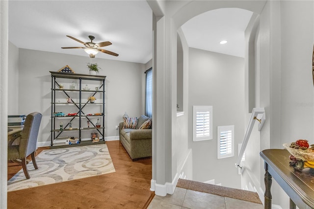 interior space with arched walkways, ceiling fan, baseboards, and wood finished floors