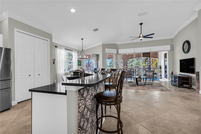 kitchen featuring a sink, dark countertops, crown molding, and freestanding refrigerator
