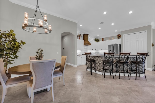 dining area with arched walkways, an inviting chandelier, ornamental molding, and recessed lighting