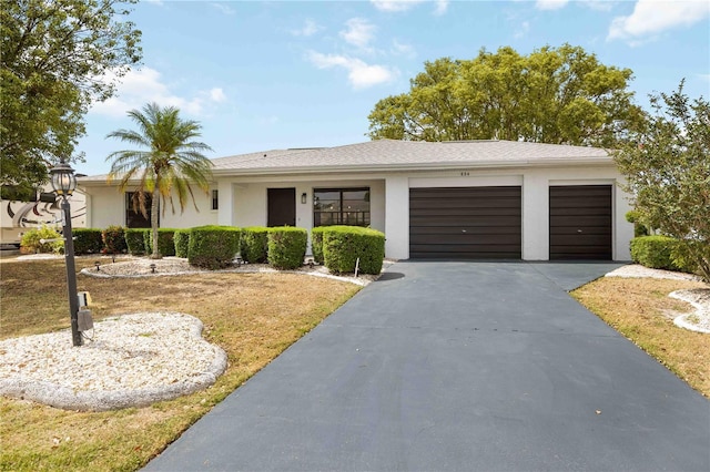 ranch-style home featuring a garage, stucco siding, driveway, and a front yard