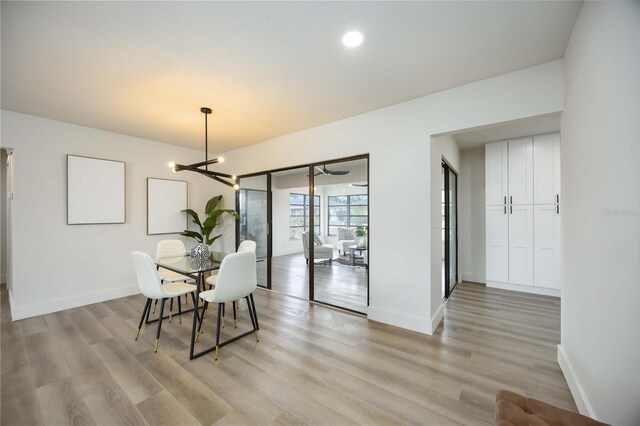 dining space with baseboards, a chandelier, and light wood finished floors