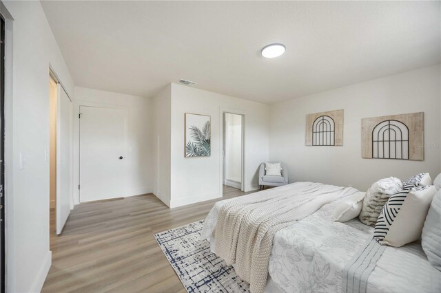 bedroom featuring baseboards, visible vents, and light wood finished floors