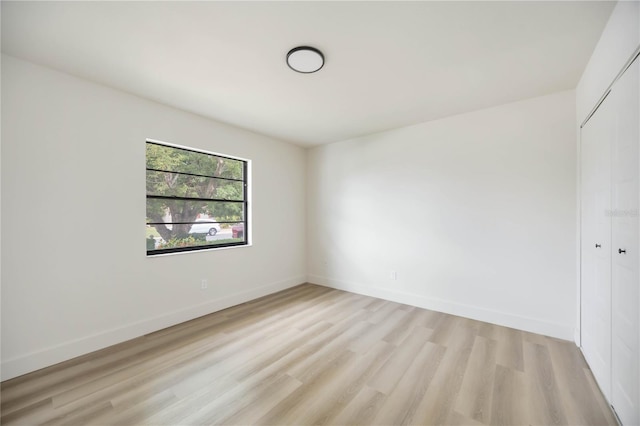 spare room with baseboards and light wood-type flooring