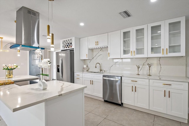 kitchen featuring appliances with stainless steel finishes, a sink, decorative backsplash, island exhaust hood, and visible vents