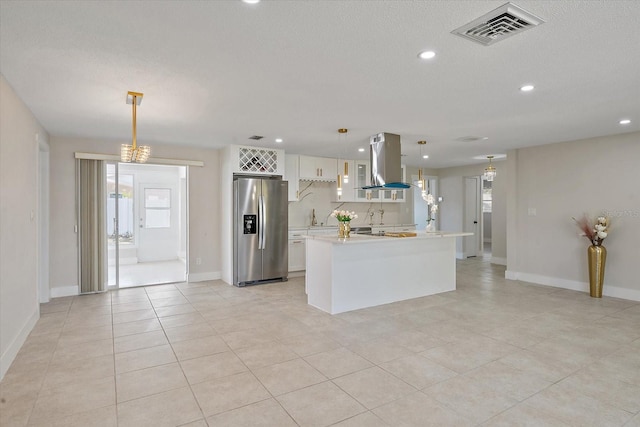 kitchen featuring visible vents, island range hood, light countertops, white cabinetry, and stainless steel fridge with ice dispenser
