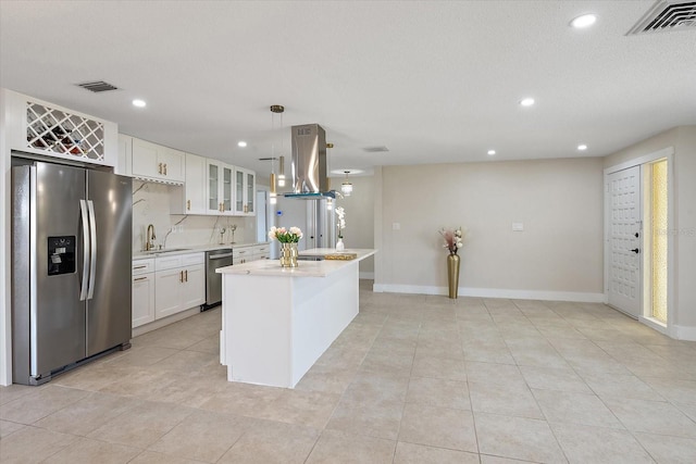 kitchen with visible vents, island range hood, light countertops, white cabinetry, and appliances with stainless steel finishes