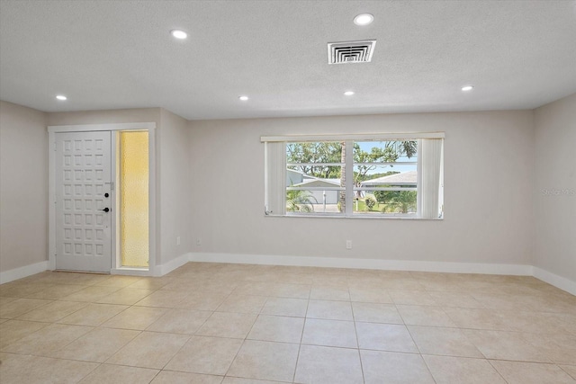 tiled empty room with visible vents, recessed lighting, a textured ceiling, and baseboards