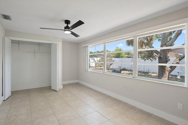 unfurnished bedroom featuring visible vents, a closet, light tile patterned flooring, baseboards, and a ceiling fan
