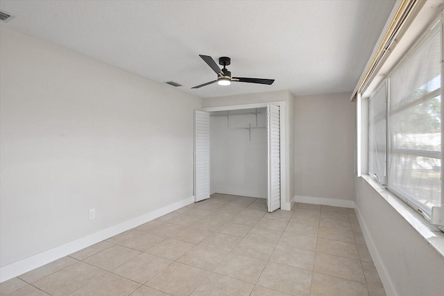 unfurnished bedroom with visible vents, a ceiling fan, light tile patterned flooring, and a closet