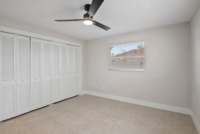 unfurnished bedroom featuring baseboards, a ceiling fan, light tile patterned floors, and a closet