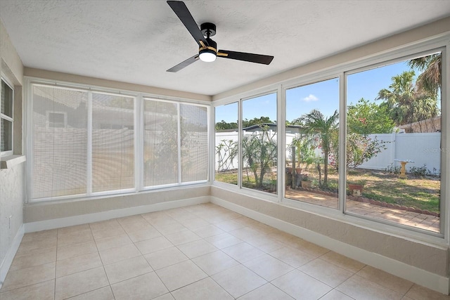 unfurnished sunroom with baseboards, tile patterned floors, a textured ceiling, and a wealth of natural light