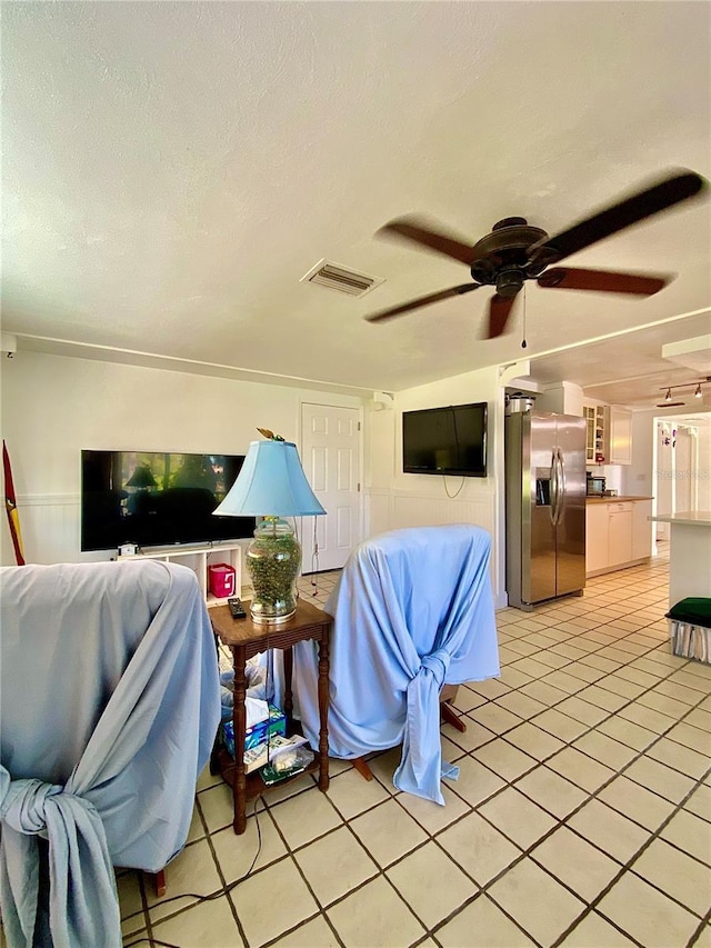living room featuring light tile patterned floors, a ceiling fan, a textured ceiling, and visible vents