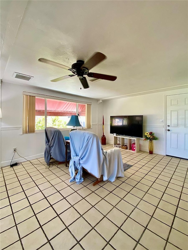 living room featuring visible vents, wainscoting, and ceiling fan