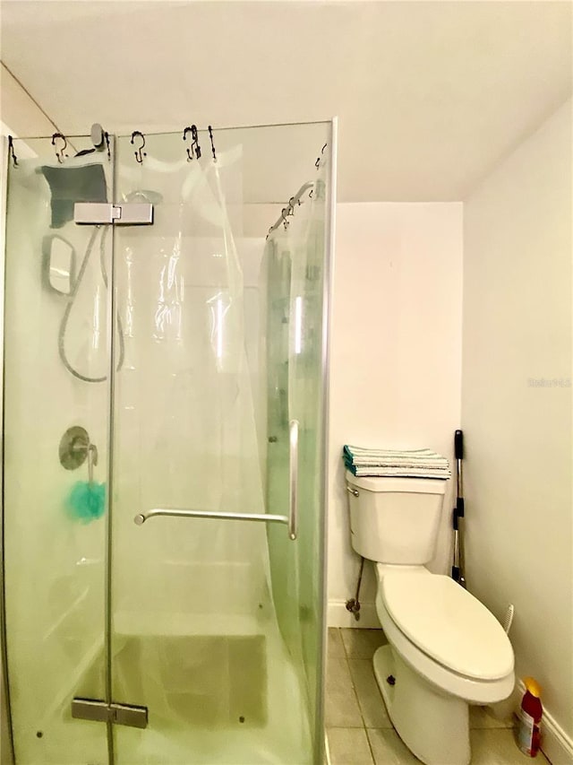 full bathroom featuring baseboards, tile patterned flooring, a stall shower, and toilet