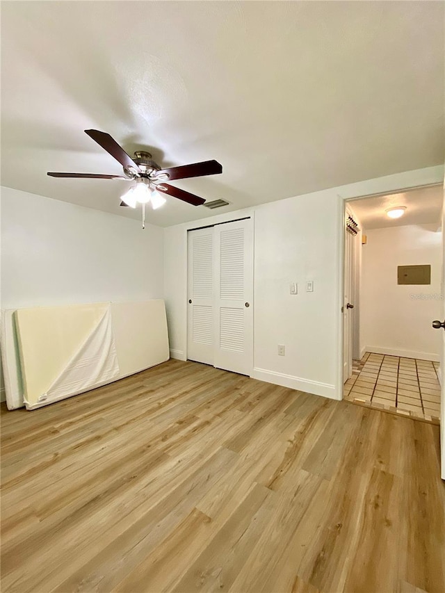 unfurnished bedroom featuring ceiling fan, visible vents, light wood-type flooring, baseboards, and a closet
