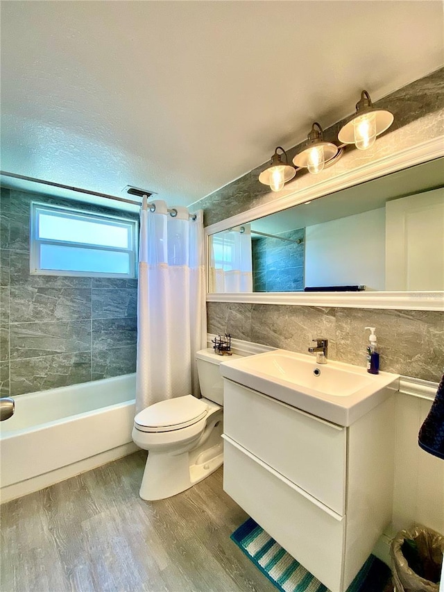bathroom with vanity, wood finished floors, toilet, tile walls, and shower / bathtub combination with curtain