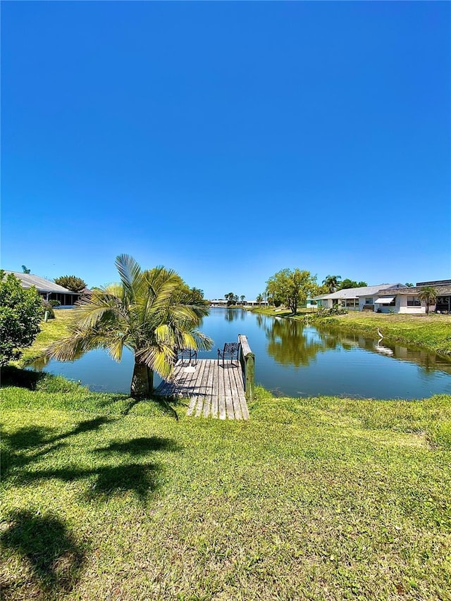view of dock featuring a lawn and a water view