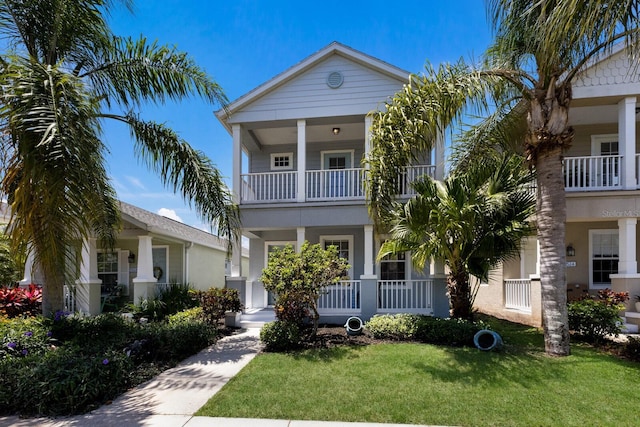 view of front facade featuring a front lawn, stucco siding, a balcony, and covered porch