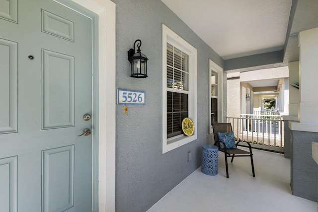 doorway to property with covered porch and stucco siding